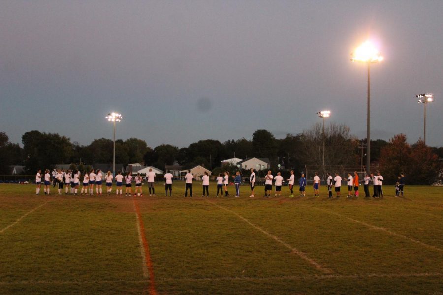 The students (left) and faculty (right) line up side by side at the start of the game.